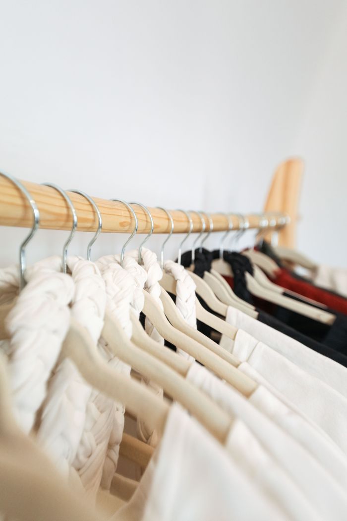 A row of elegant garments on hangers in a minimalist wardrobe setting.