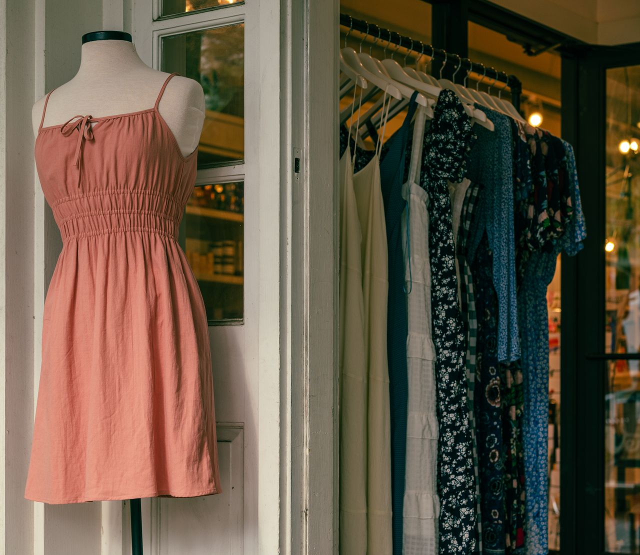 heros-img Mannequin with a pink dress and clothing rack in a stylish boutique.